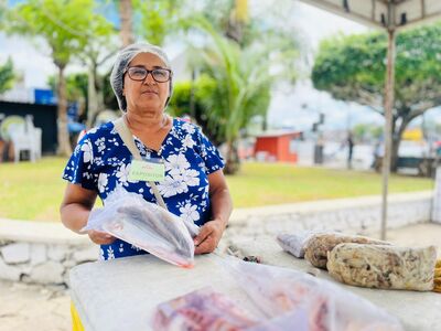 A 6ª edição da Feira Santa do Pescado começou movimentando a Praça Admar Braga Guimarães, a conhecida Praça dos Táxis, em Valença, nesta quinta-feira (26). Logo no primeiro dia, o espaço foi tomado pela diversidade de produtos locais, reunindo pescadores, artesãos e instituições. A iniciativa também contou com o apoio de diversas secretarias municipais, que contribuíram para uma programação ainda mais diversa. Entre os expositores, Dona Maria Pereira, conhecida como Cida do Marisco, apresentou produtos frescos e de qualidade, reforçando a tradição da pesca familiar. O público também pôde conhecer o universo do aquarismo com o stand da Betta Premium, representado por Ylan Leocadia e Lucas Paraíso, que expuseram peixes ornamentais e acessórios. No artesanato, Jacinete de Jesus, da marca Crochê da Jacy, apresentou peças como saias, camisas e vestidos, resultado de mais de cinco anos de dedicação ao artesanato. Já Cláudia Cardoso, com mais de 25 anos de experiência no crochê, destacou o ofício como fonte de “equilíbrio e saúde mental”. O Núcleo do Artesanato Territorial da Costa do Dendê, também esteve presente, com produtos confeccionados em sisal e juta, valorizando a produção regional. A diversidade também esteve presente no cultivo de plantas. Marle Pereira, que há cinco anos comercializa espécies cultivadas em seu próprio sítio, levou para a feira exemplares como rosas do deserto, orquídeas e antúrios vermelhos. Com orgulho, ela contou que a renda obtida com as vendas contribui para custear a faculdade de psicologia da filha.